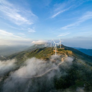 Wind Turbines sit atop a hill with low clouds.