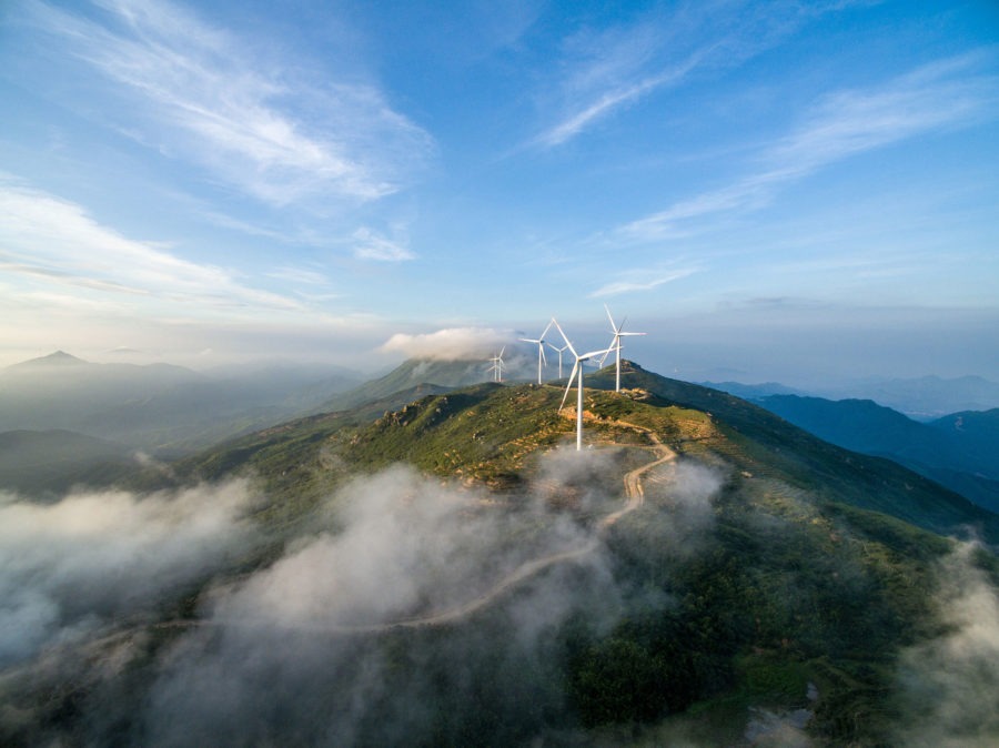 Wind Turbines sit atop a hill with low clouds.