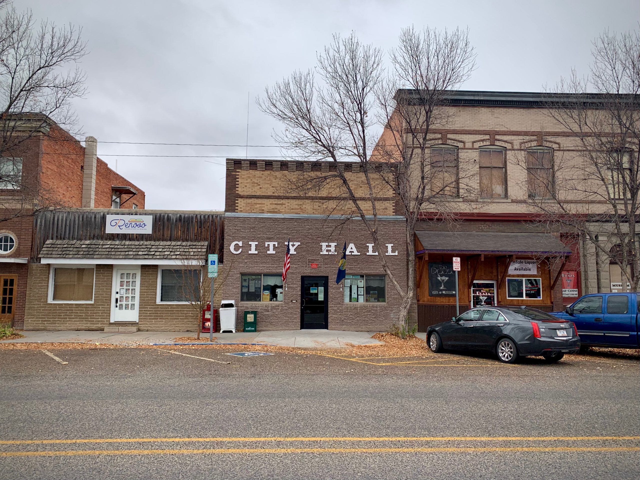 Photo of the City Hall in Three Forks, Montana. Cloudy fall day, cars are parked along street.
