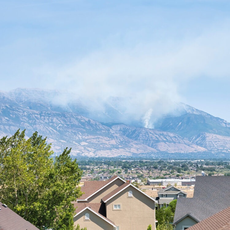 Smoke rises from a hillside above a community in Utah's Wasatch Valley.